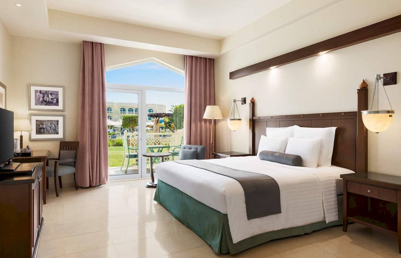 Wyndham Garden Salalah Mirbat Hotelzimmer mit Bett, Schreibtisch, Fernseher und Balkon.