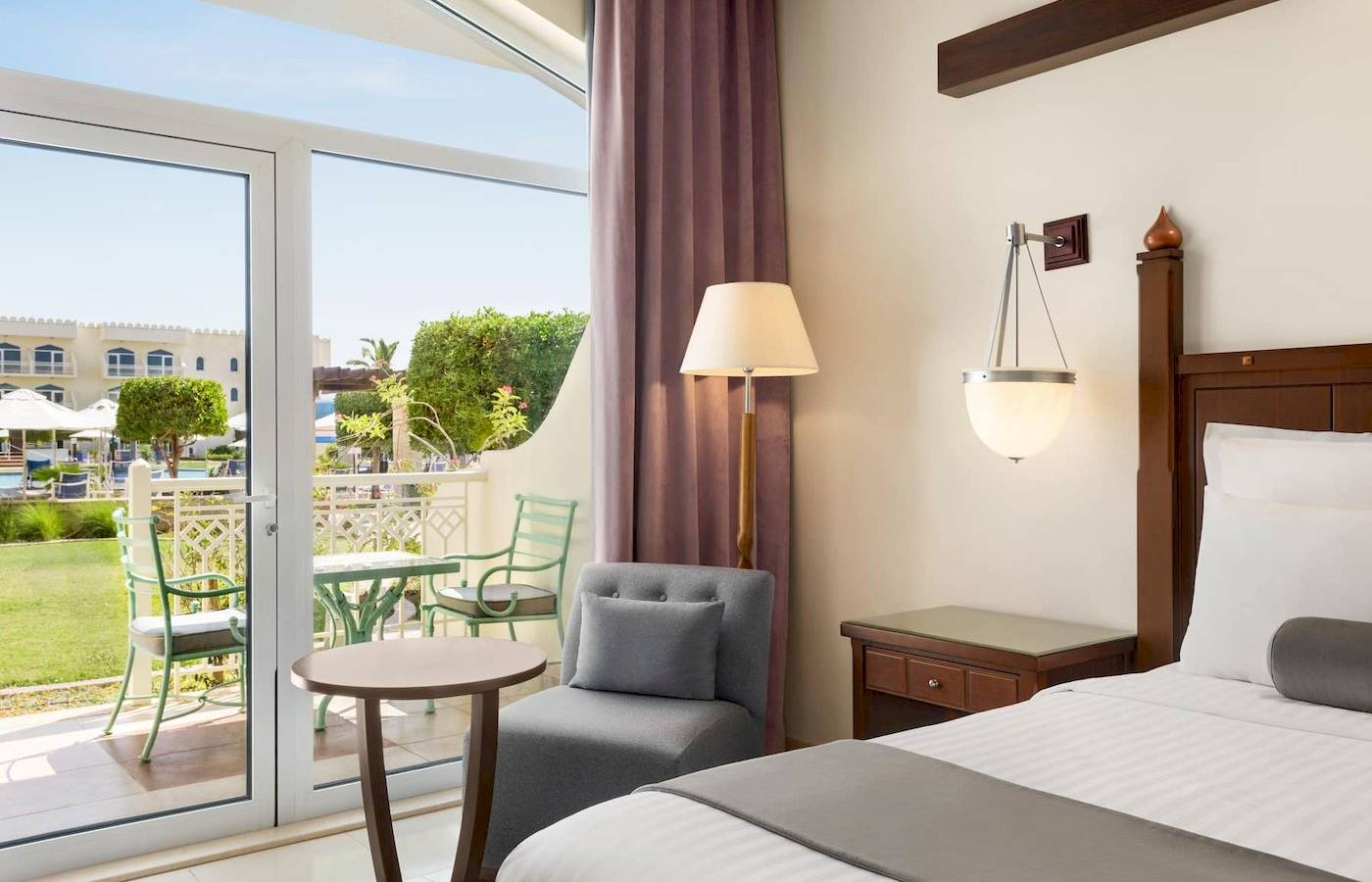 Zimmer im Wyndham Garden Salalah Mirbat Hotel mit Blick auf eine Terrasse und Garten.
