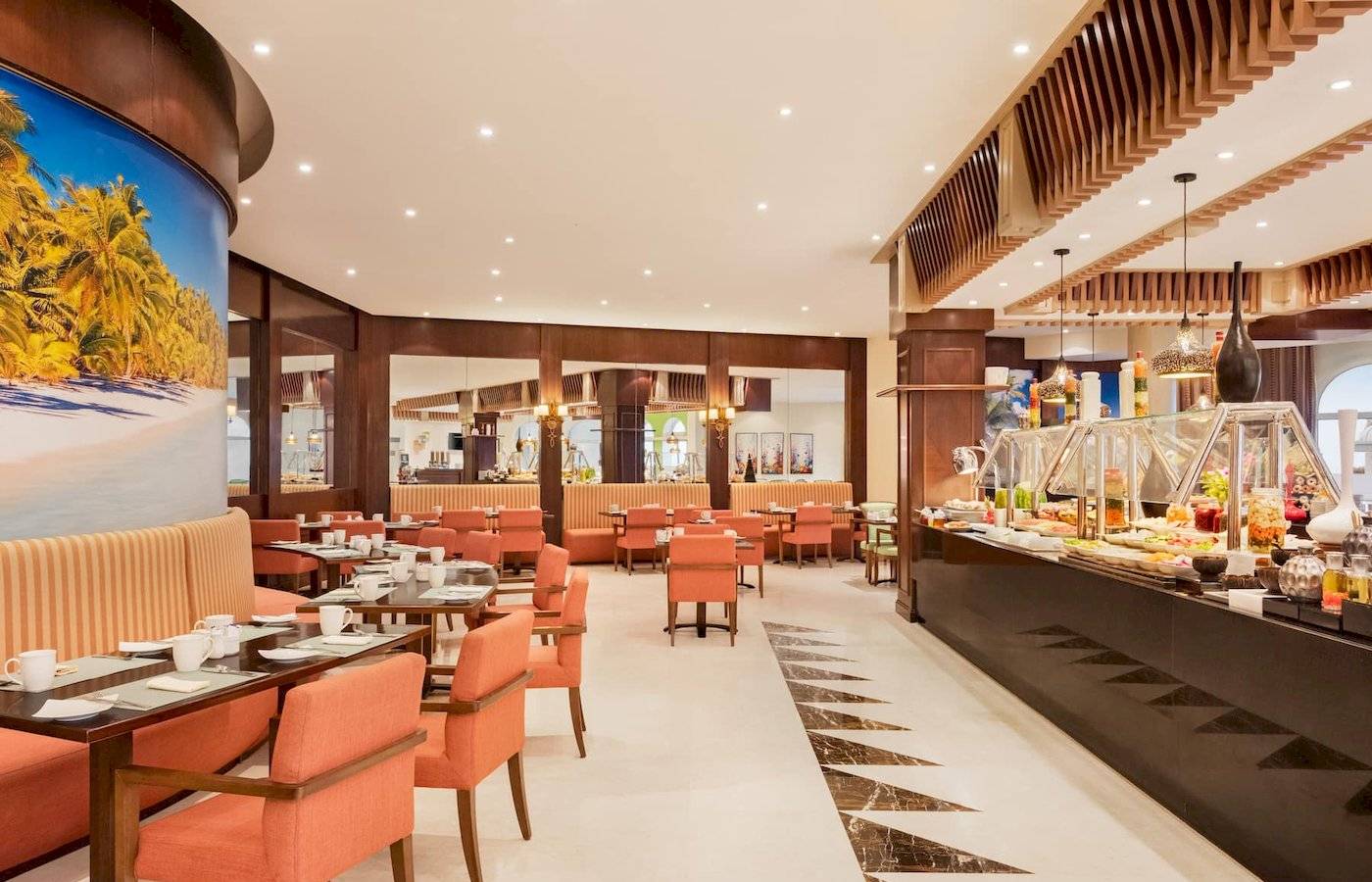 Restaurant des Wyndham Garden Salalah Mirbat Hotels mit orangen Stühlen und Tischen.