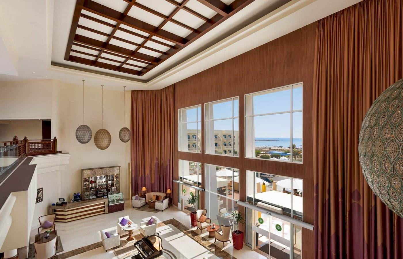 Einblick in die Lobby des Wyndham Garden Salalah Mirbat Hotels mit Innendekoration, Fenstern und Meerblick.