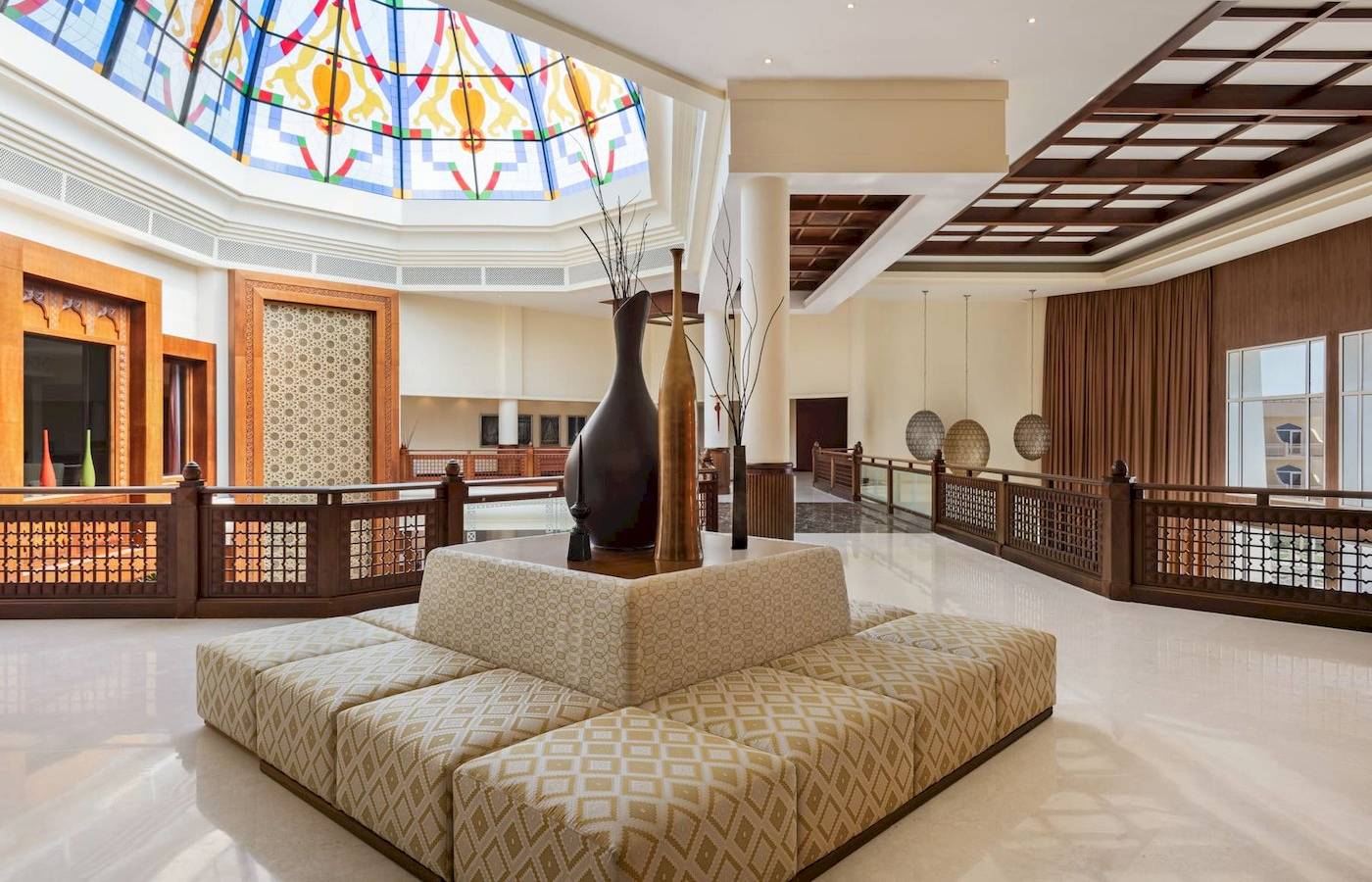 Empfangshalle des Wyndham Garden Salalah Mirbat mit Sitzecke, Vasen und buntem Glasdach
