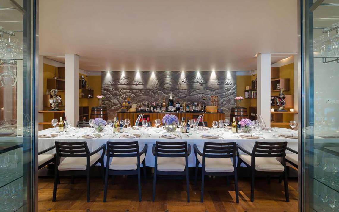 Ein elegantes Esszimmer im One & Only Reethi Rah mit einer langen Tafel, gedeckt für mehrere Personen, und Dekorelementen.
