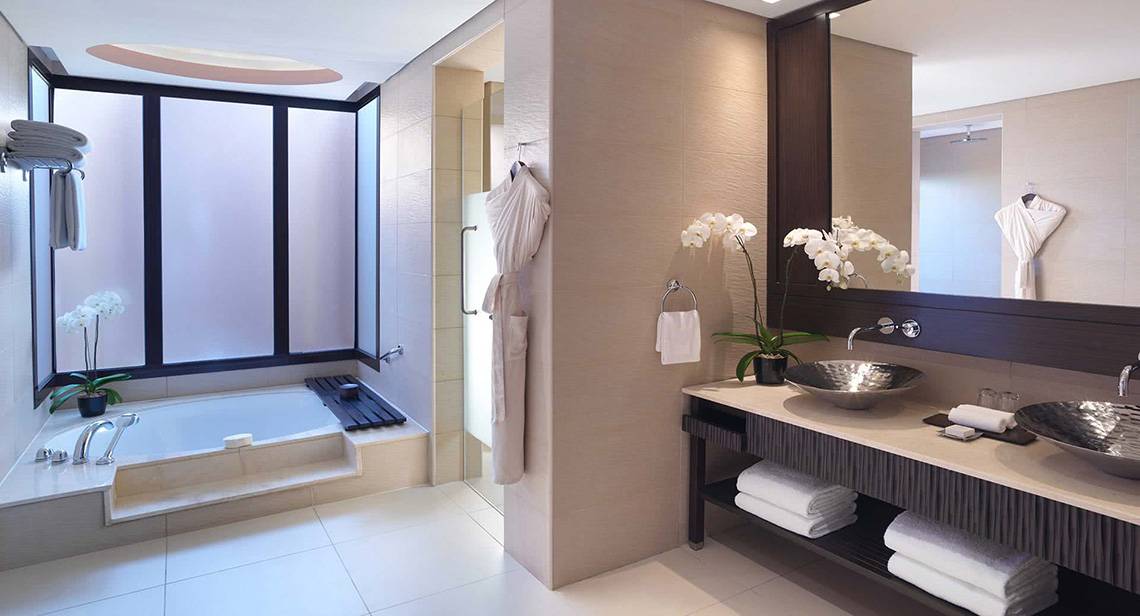Badezimmer im Anantara The Palm Dubai Resort mit Badewanne, Waschbecken und Spiegel.