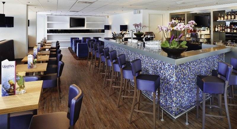 Die Bar im Casa Amsterdam Hotel mit blauen Stühlen und einer Theke mit blauen Mosaiken.