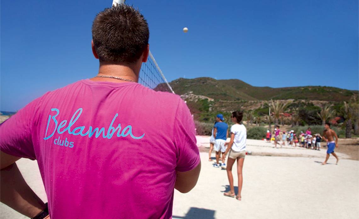 Rückansicht eines Mannes in einem rosa Belambra Clubs T-Shirt, der auf ein Volleyballspiel blickt.