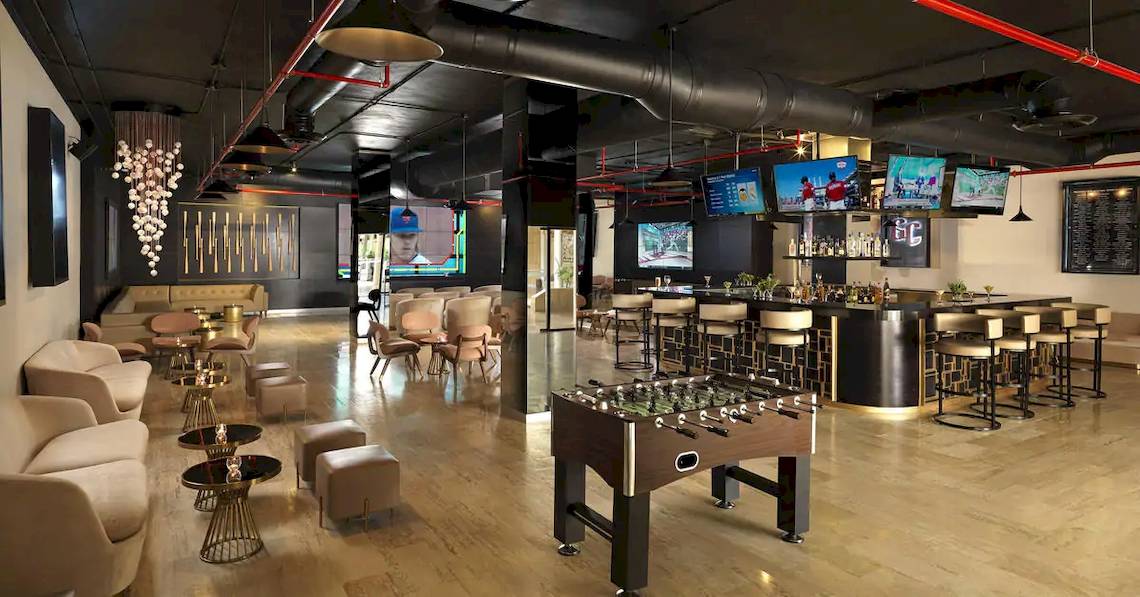Loungebereich des Melia Caribe Beach Resorts mit Fernsehern, Bar, Fußballtisch und Möbeln.