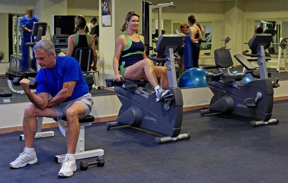 Fitnessstudio mit Männern und Frauen auf Stepper und Gewichtstraining