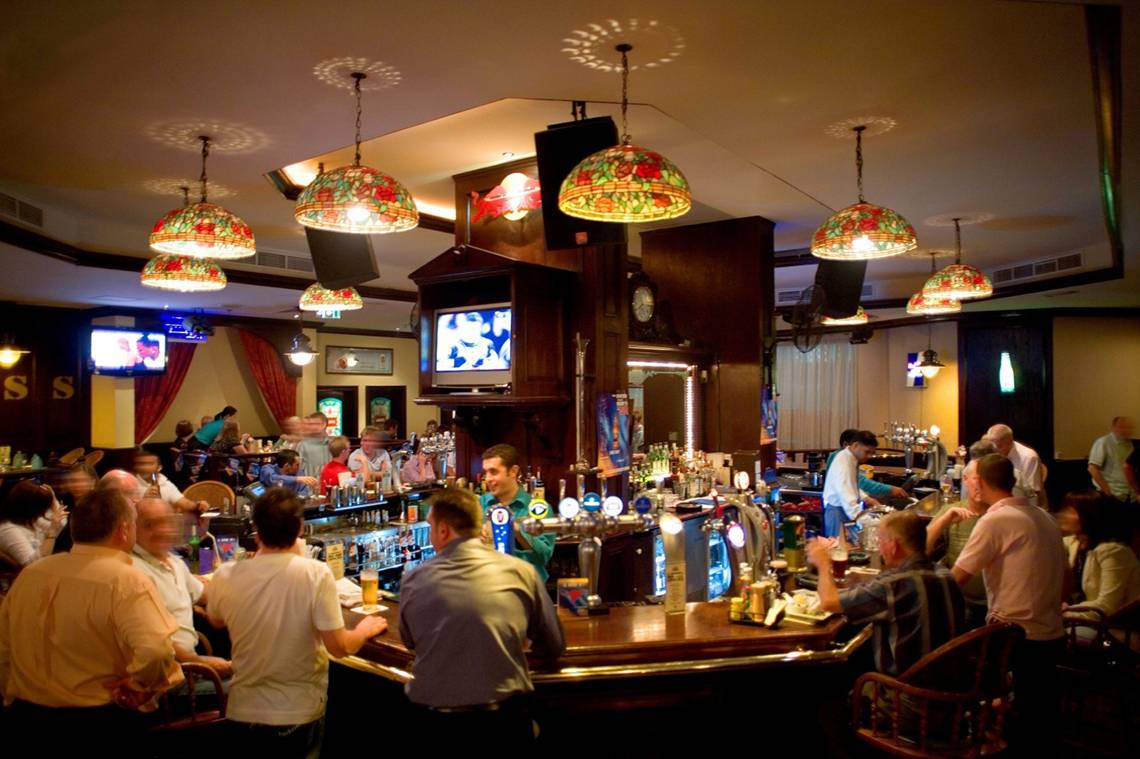 Barszene im Jumeira Rotana mit vielen Gästen, die an der Theke sitzen und trinken.