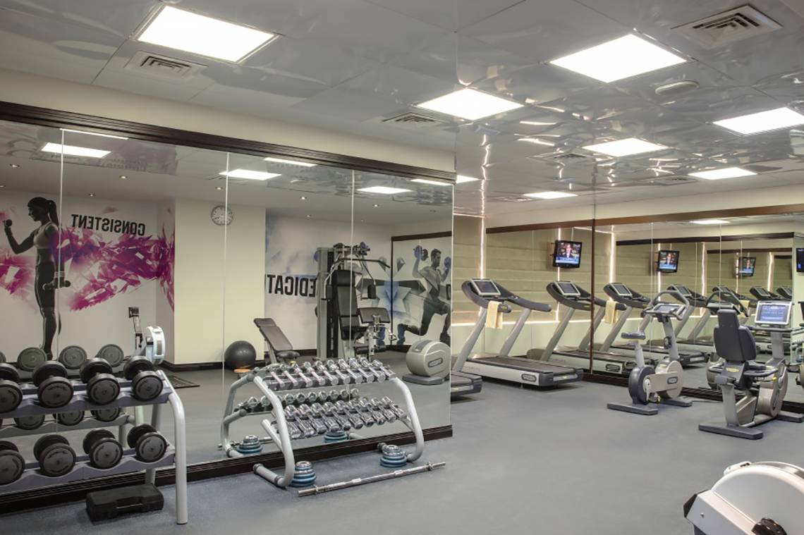 Fitnesscenter im Jumeira Rotana Hotel mit Laufbändern, Hanteln und anderen Trainingsgeräten.