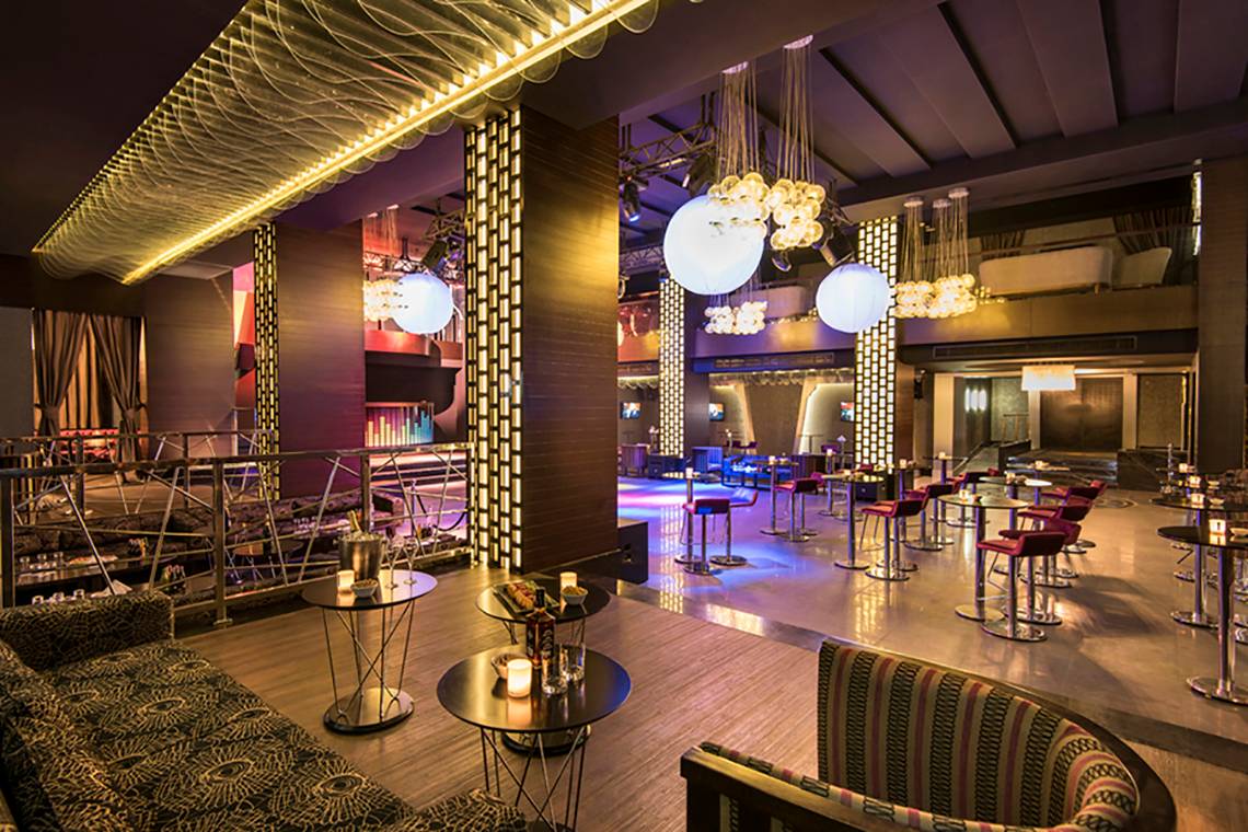 Innenbereich des Rixos Bab Al Bahr Hotels mit Loungebereich, Tischen und Stühlen.