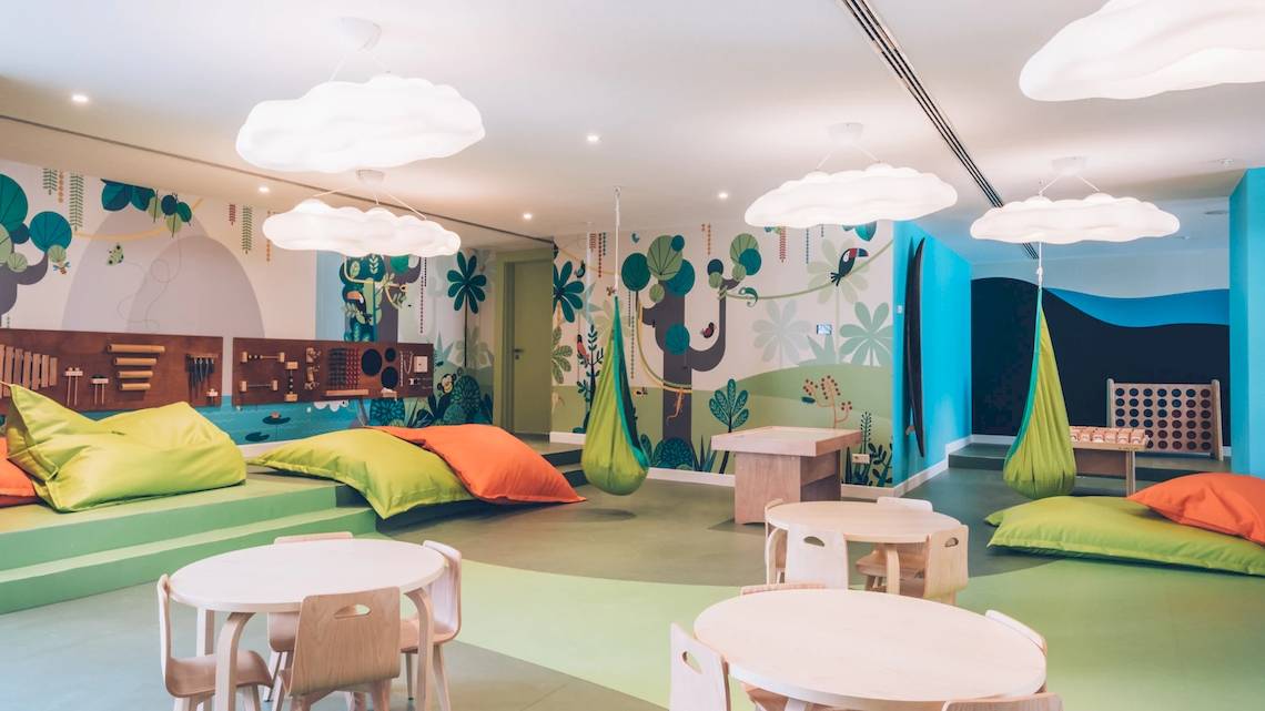 Kinderzimmer im Iberostar Waves Alcudia Park Hotel mit farbenfrohen Wänden, bunten Hängematten und gemütlichen Sitzecken.