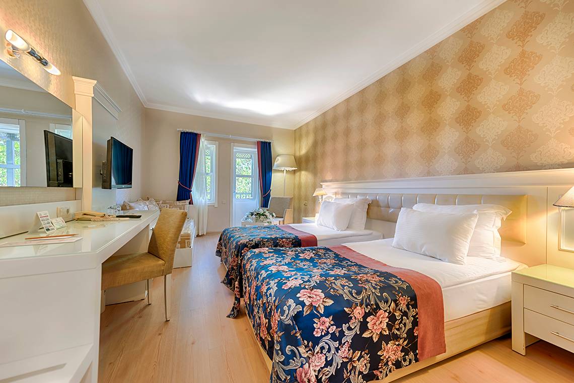 Zwei Betten mit blumigen Bettdecken in einem Zimmer im Club Nena Hotel
