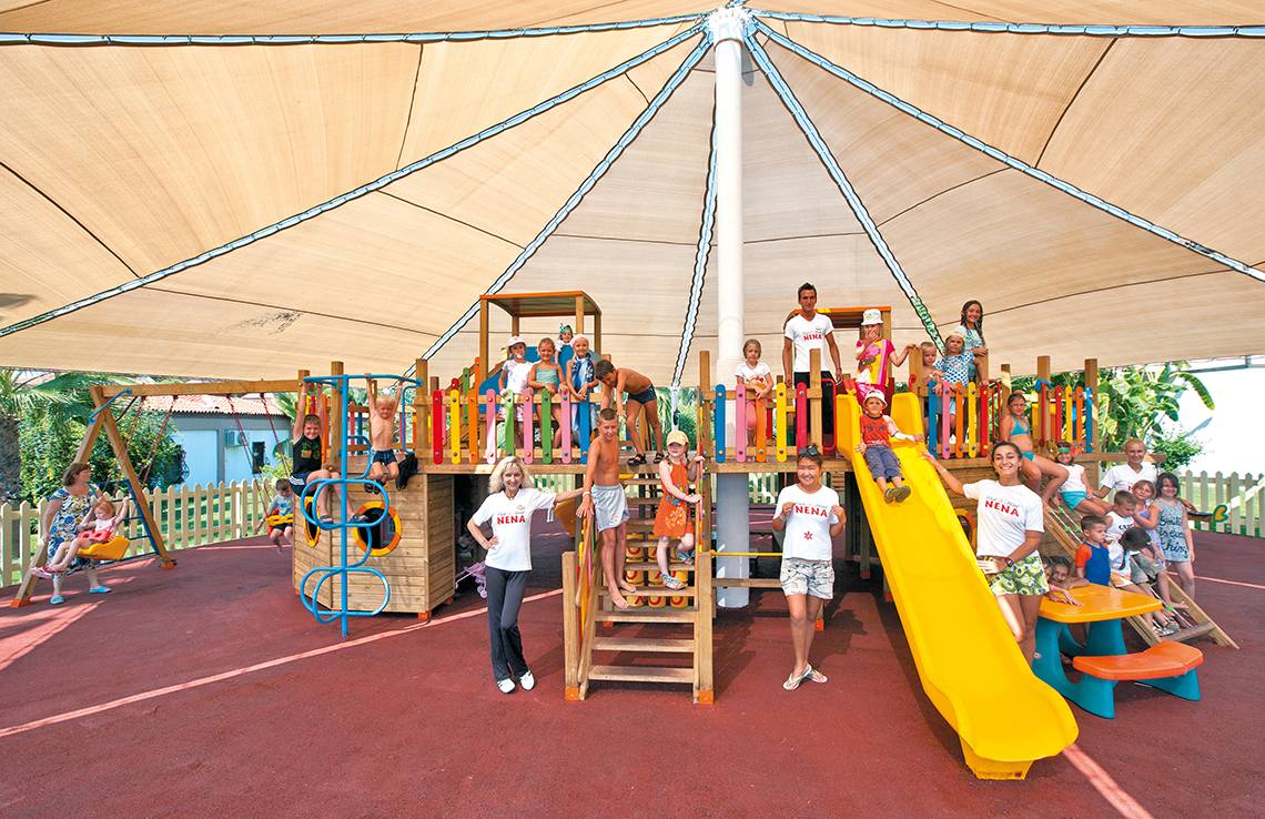 Familien und Kinder spielen auf einem überdachten Spielplatz im Club Nena.