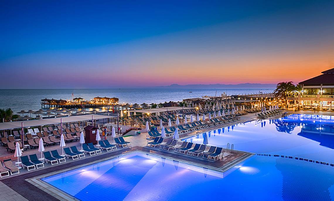 Abendlicher Pool im Club Nena Resort mit vielen Sonnenliegen und Blick aufs Meer
