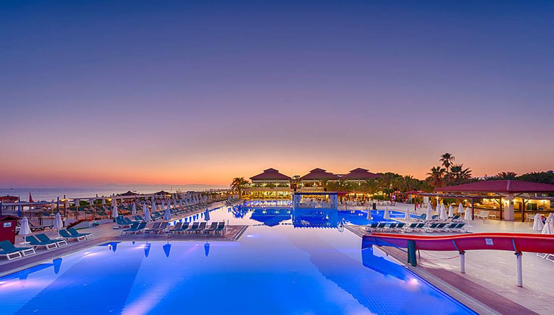 Abendstimmung am Pool im Club Nena Resort mit blau beleuchteten Wasser und Sonnenliegen