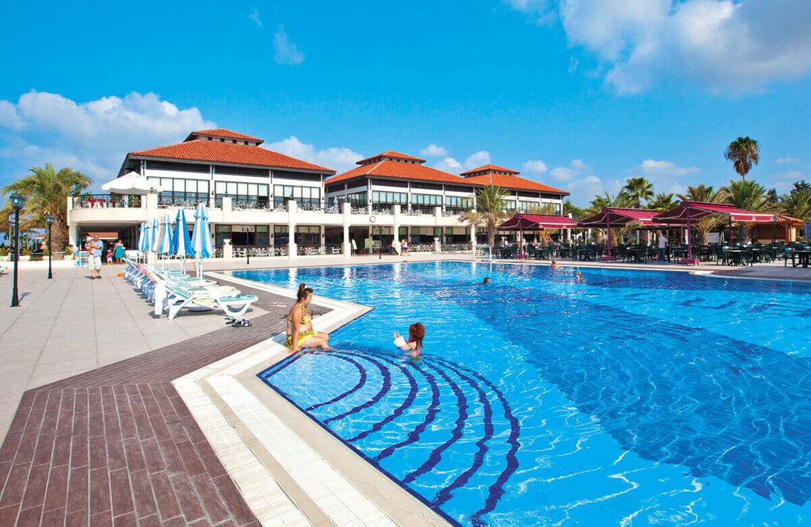 Club Nena Hotel zeigt eine große Schwimmbadanlage mit Gästen vor dem Gebäude.