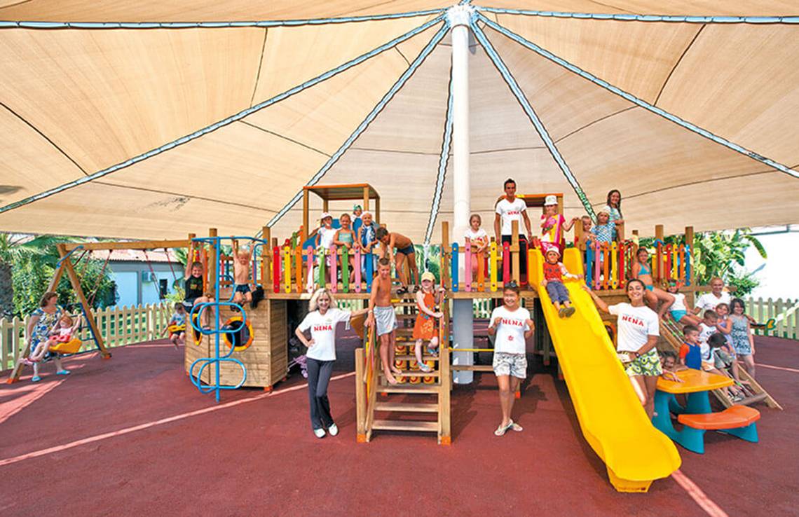 Foto von Kindern und Mitarbeitern im Spielplatz des Club Nena Hotels bei Dämmerung