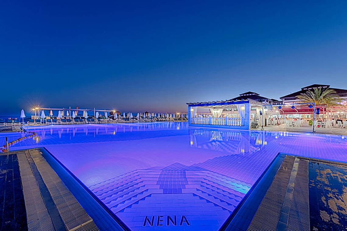 Pool des Club Nena Hotels bei Nacht mit blauer Beleuchtung und Loungebereich im Hintergrund