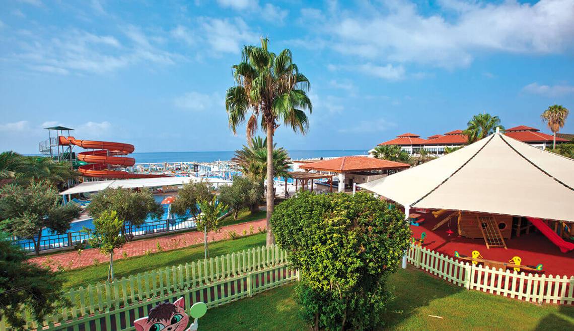 Aussicht auf den Wasserpark des Club Nena mit Rutschen, Gebäuden und Meer im Hintergrund.