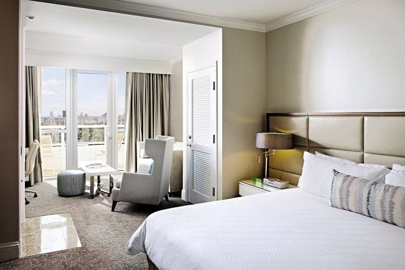 Innenansicht eines Zimmers im Fontainebleau Miami Beach Hotel mit Bett, Stühlen und Stadtblick
