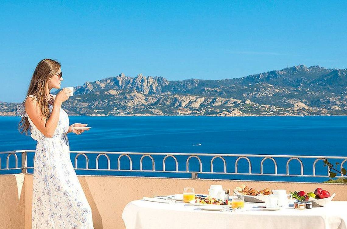 Frau genießt Frühstück auf dem Balkon im Resort Cala Di Falco mit Meerblick