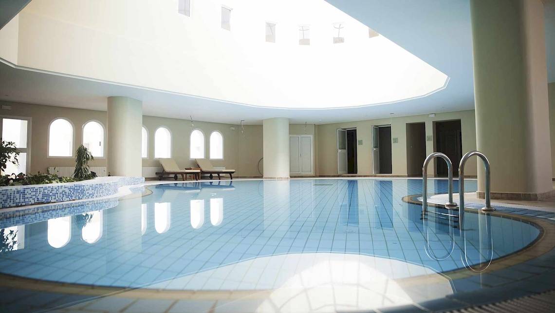 Innenpool des Robinson Djerba Bahiya Hotels mit blauen Fliesen und Loungemöbeln.
