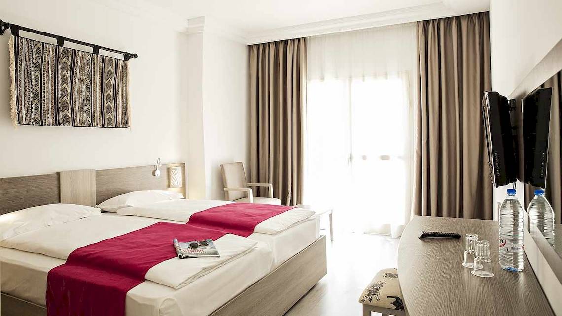 Zimmer im Robinson Djerba Bahiya Hotel mit zwei Betten, Dekor und Möbeln.
