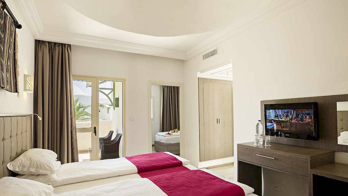Zimmer im Robinson Djerba Bahiya Hotel mit zwei Betten, Fernseher und einem Schreibtisch.