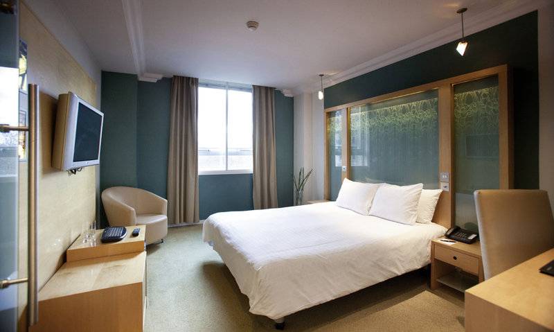 Hotelzimmer im Cumberland mit Bett, Fernseher, Schreibtisch und Stuhl
