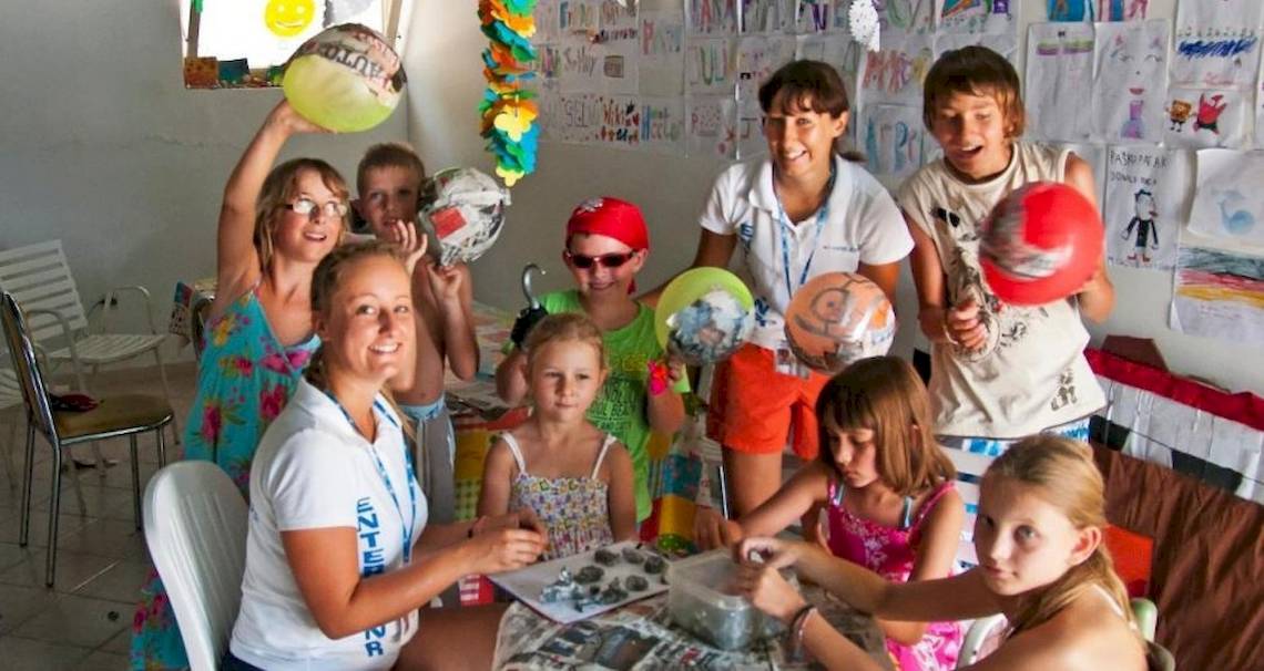 Gruppe von Kindern und Erwachsenen, die einen Workshop im Hotel Osmine Slano veranstalten, halten Ballons und malen.
