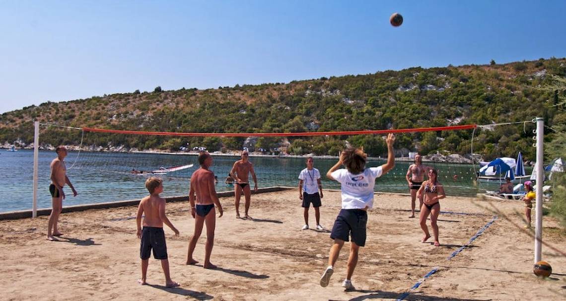 Mehrere Personen spielen Volleyball auf einem Strand in der Nähe des Osmine Slano Hotels.