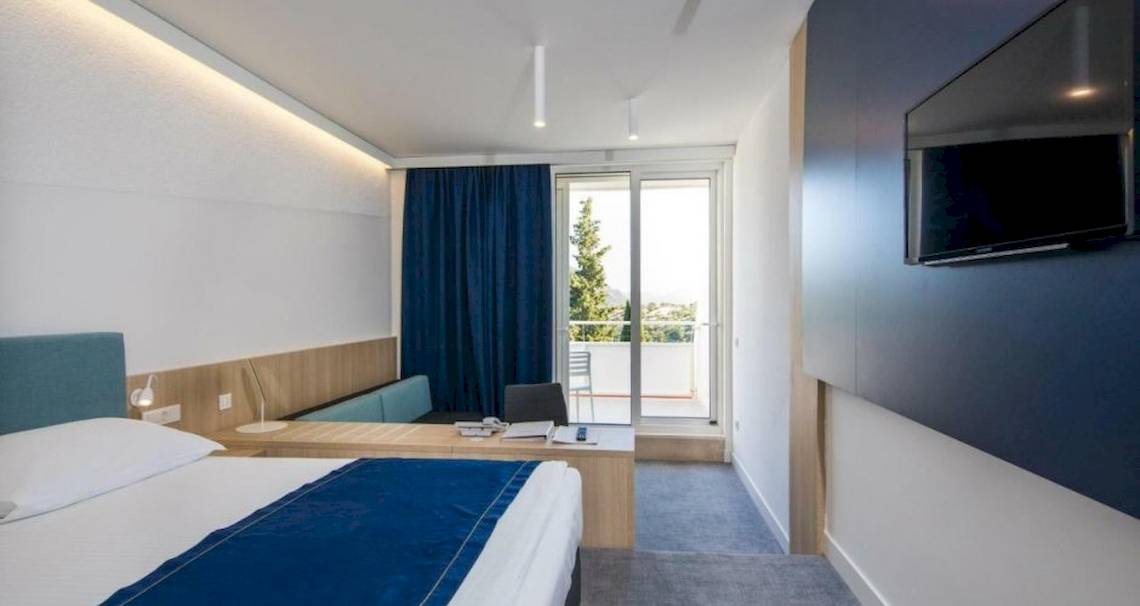 Hotelzimmer im Osmine Slano mit Bett, Schreibtisch, Fernseher und Balkon.