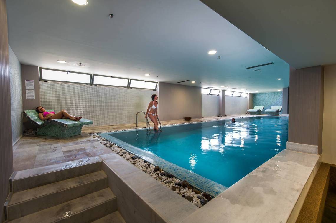Ein mädchen steht im innenpool des akti-palastes und ein anderes mädchen liegt auf einer liege
