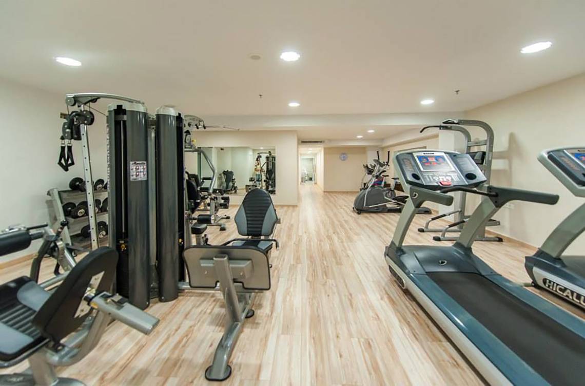 Fitnessbereich im Akti Palace Hotel mit verschiedenen Trainingsgeräten und Holzboden.