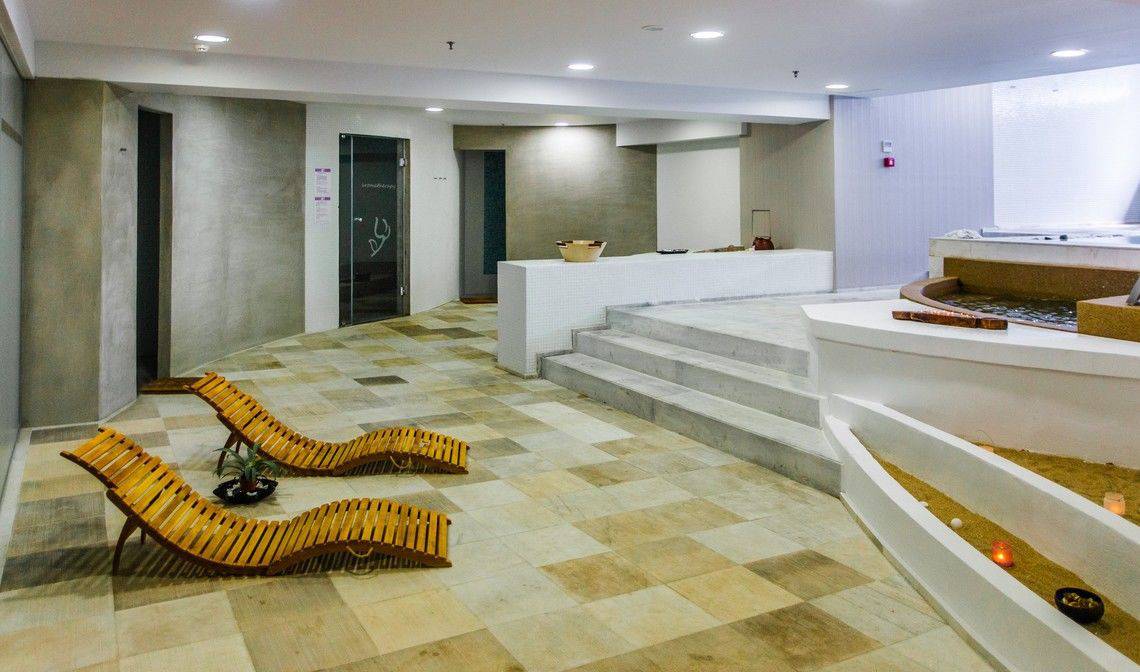 Spa-Bereich im Akti Palace Hotel mit zwei Holzliegen und einem Whirlpool.