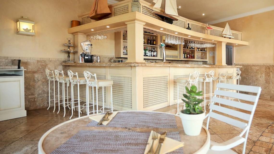 Die Bar im Iberostar Grand El Mirador Hotel mit weißer Theke, Stühlen und Flaschen.
