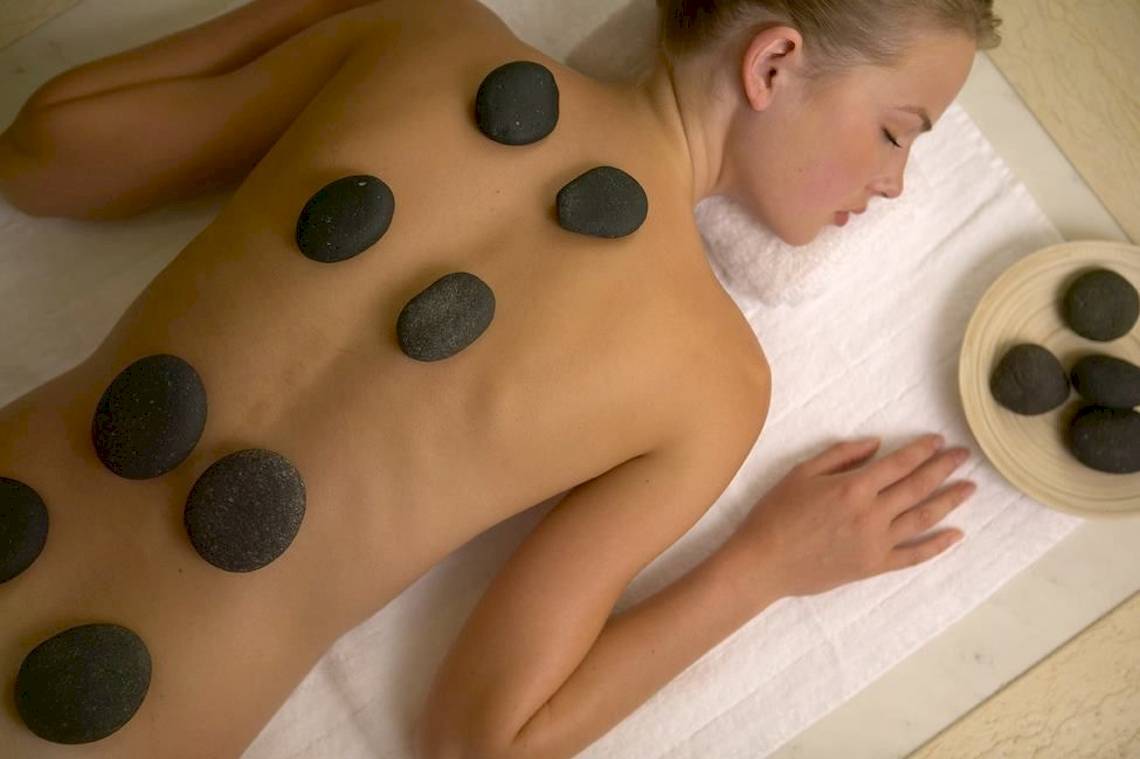 Eine Frau genießt eine Massage mit Steinen auf dem Rücken im Hotel.