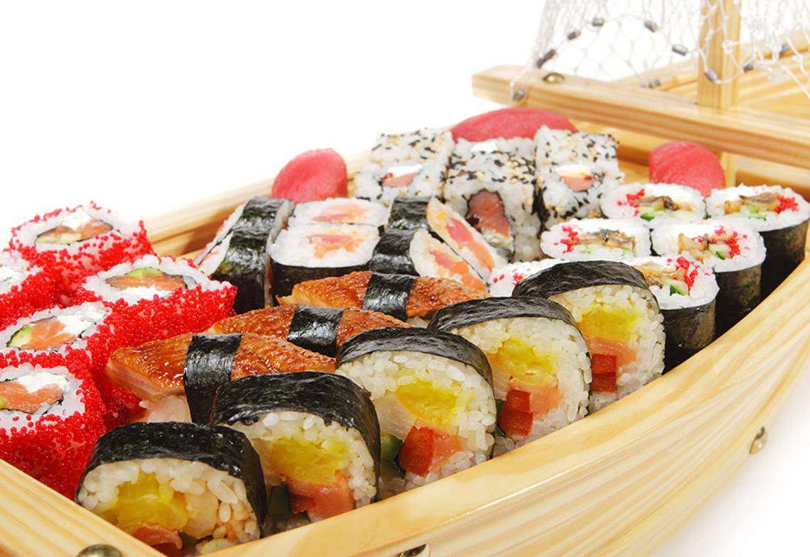 Verschiedene Sushi in einer hölzernen Bootsform präsentiert.
