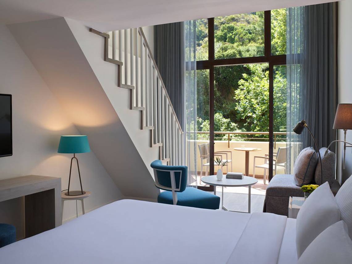 Innenansicht der Suite im Rhodes Bay Hotel mit Blick auf eine Terrasse und Außenmöbel.