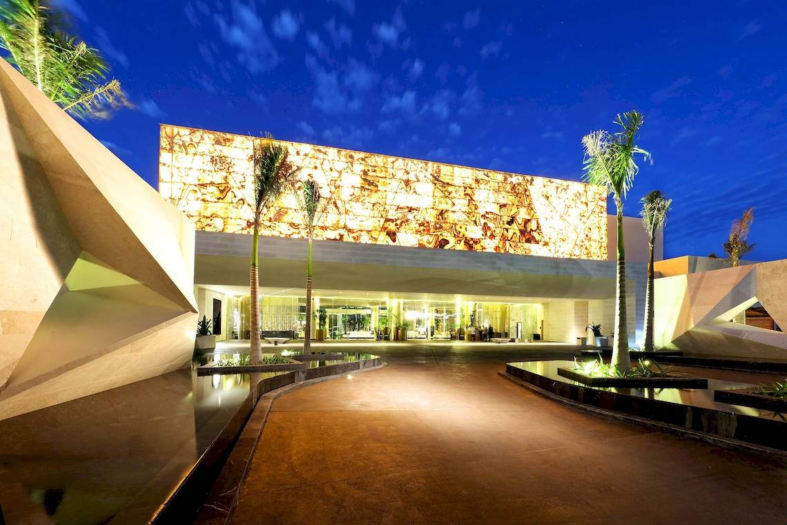 Außenansicht des TRS Coral Hotels bei Nacht mit beleuchteter Fassade und Wasserfeature
