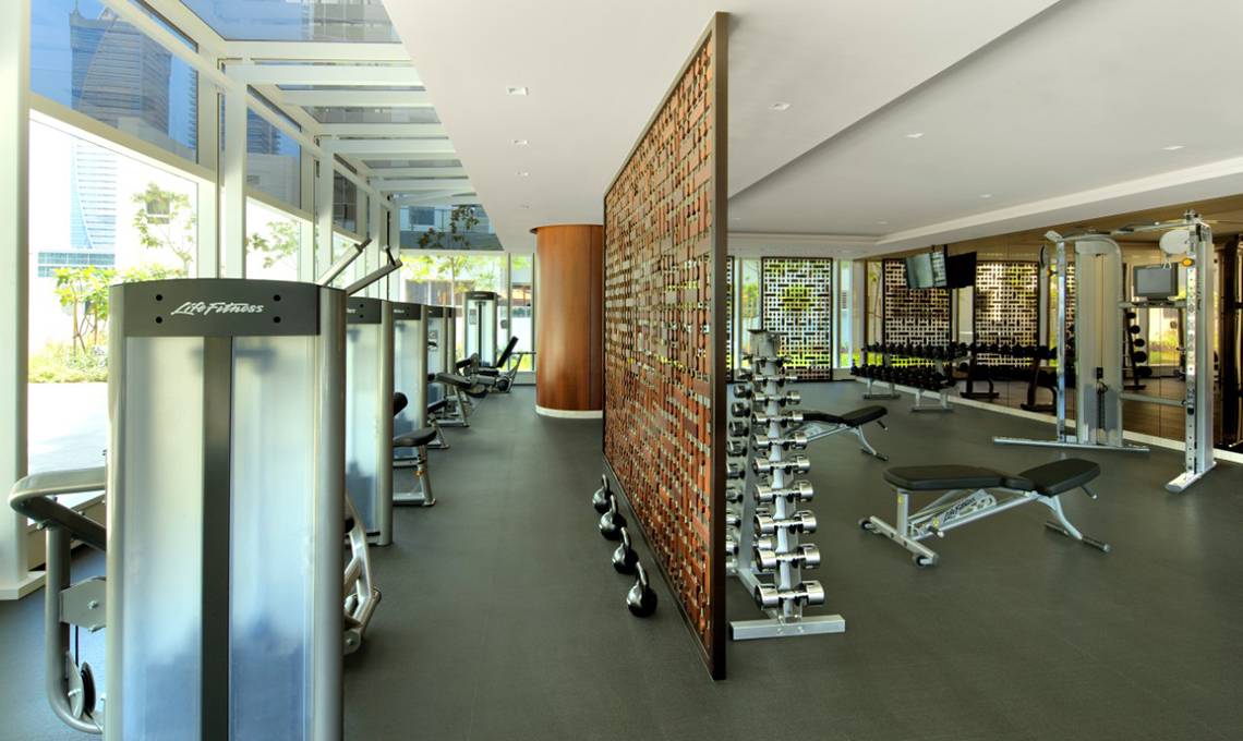 Fitnesscenter im Taj Dubai Hotel mit modernen Geräten und großem Fenster.