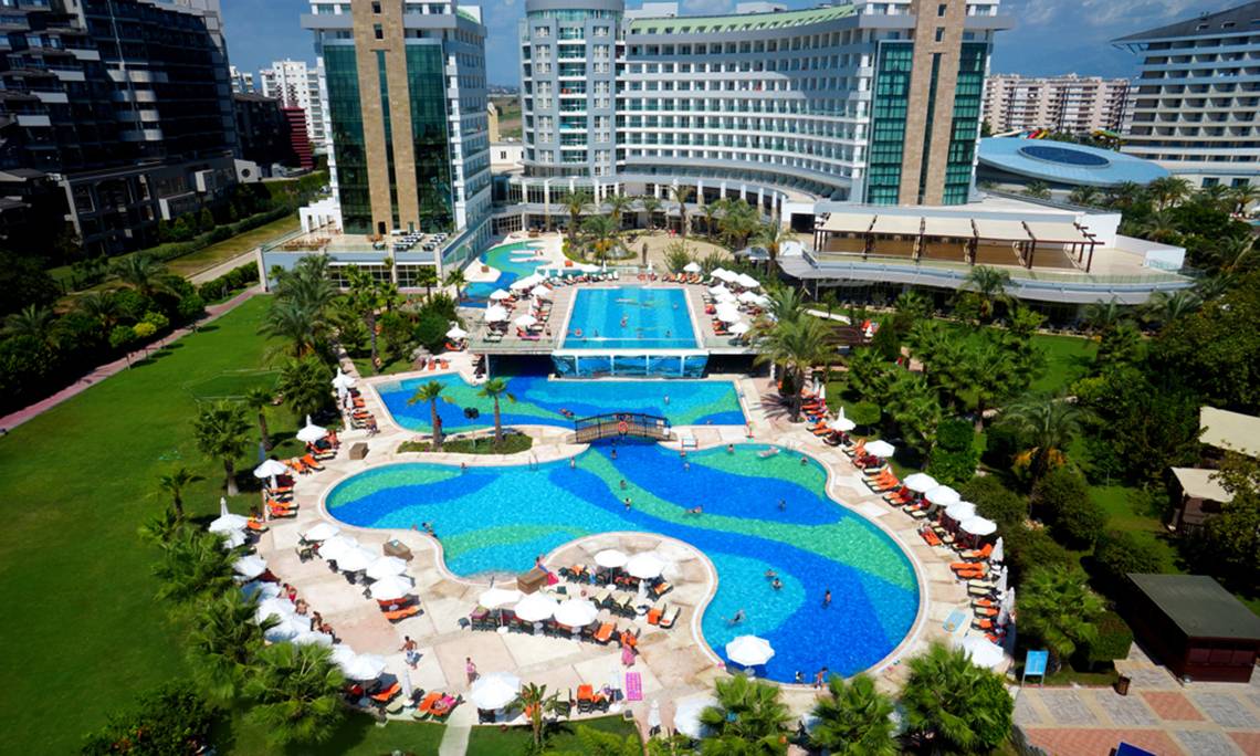 Luftaufnahme des Sherwood Exclusive Lara Hotels mit großen Pools und Sonnenliegen.