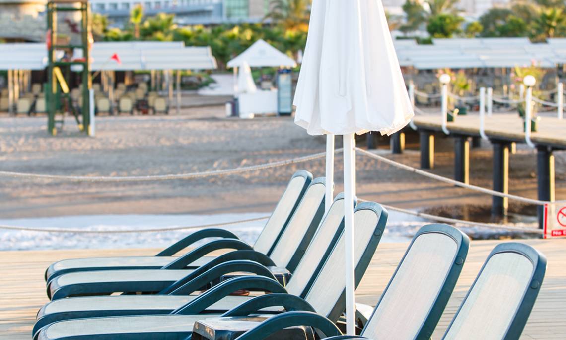 Reihe von Liegestühlen mit Sonnenschirmen auf der Terrasse des Sherwood Exclusive Lara Hotels.