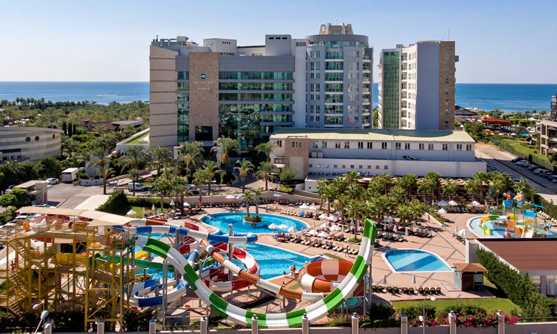 Luftaufnahme des Sherwood Exclusive Lara Hotels mit Wasserrutschen und Poolanlage am Meer