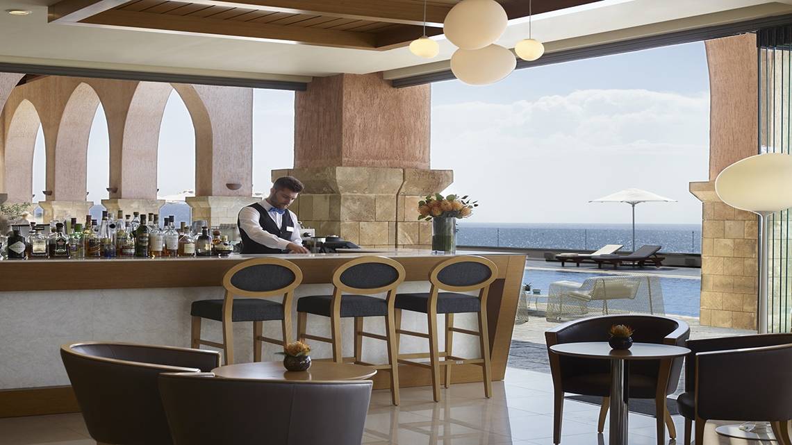 Barbereich des Boutique 5 Hotel & Spa mit Blick auf das Meer und Liegestühlen.