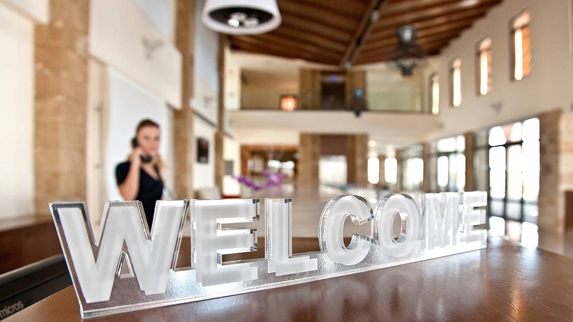 Willkommensschild des Boutique 5 Hotel & Spa mit einer Frau am Telefon im Hintergrund.