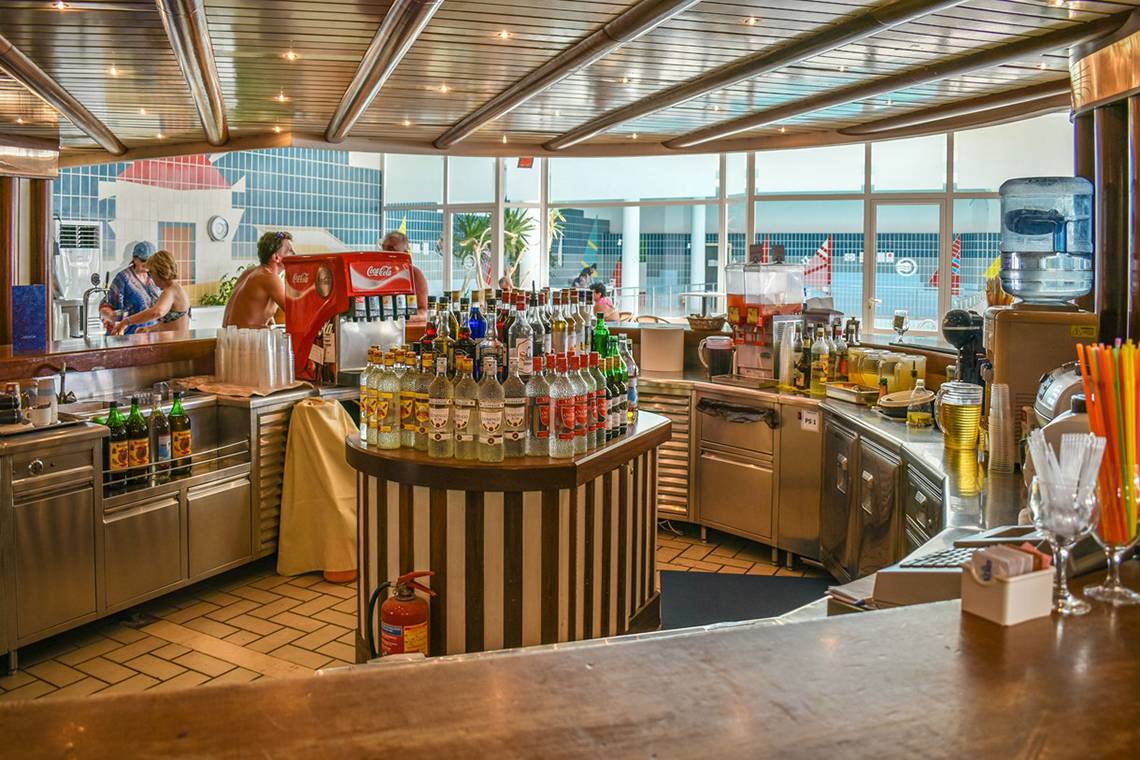 Innenansicht der Bar im Hotel Creta Star mit vollbestückten Regalen und Kunden.