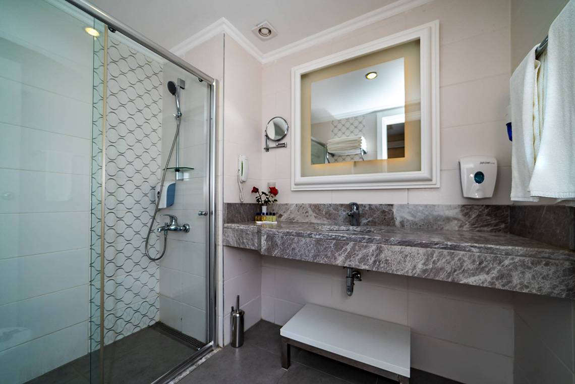 Badezimmer im Seamelia Beach Resort & Spa mit Dusche, Spiegel und Waschbecken.