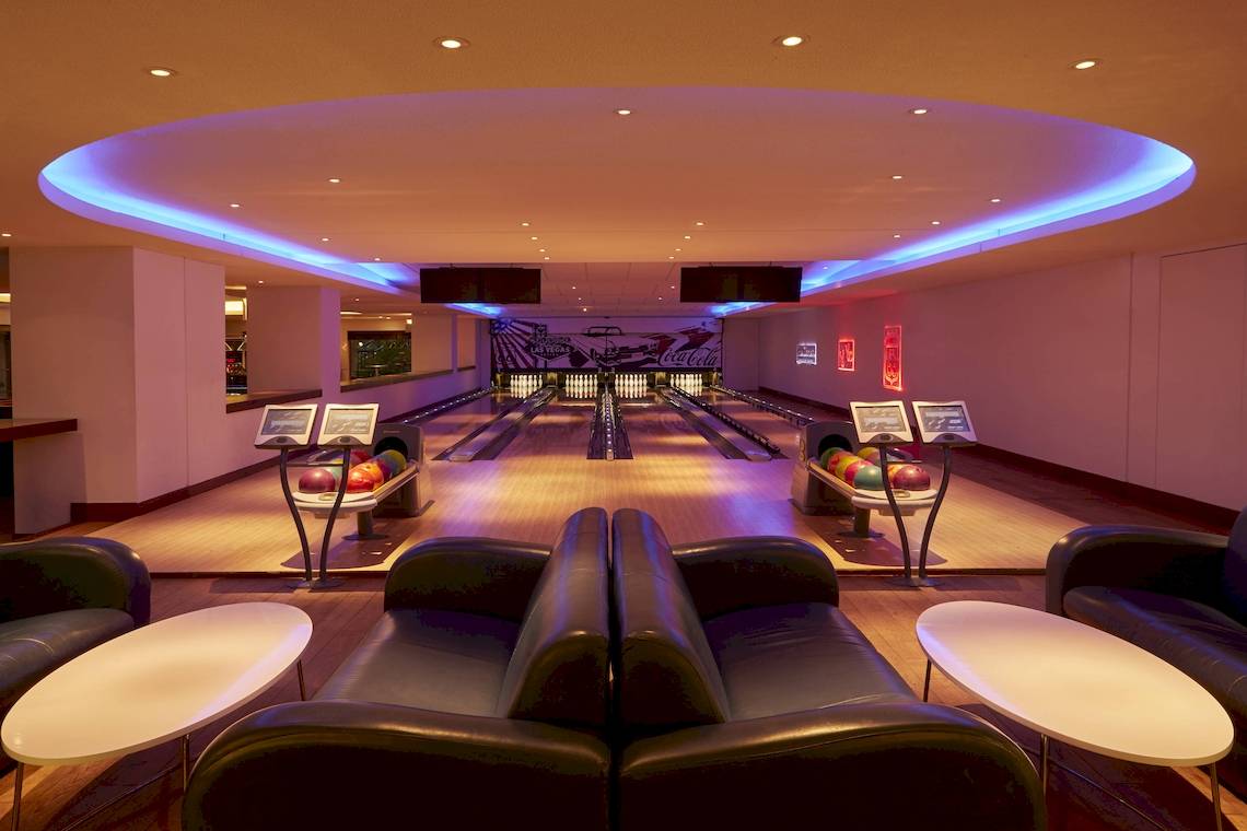 Bowlinghalle im Westin Resort, Costa Navarino mit Bowlingbahnen, leuchtenden Farben und Sofas.