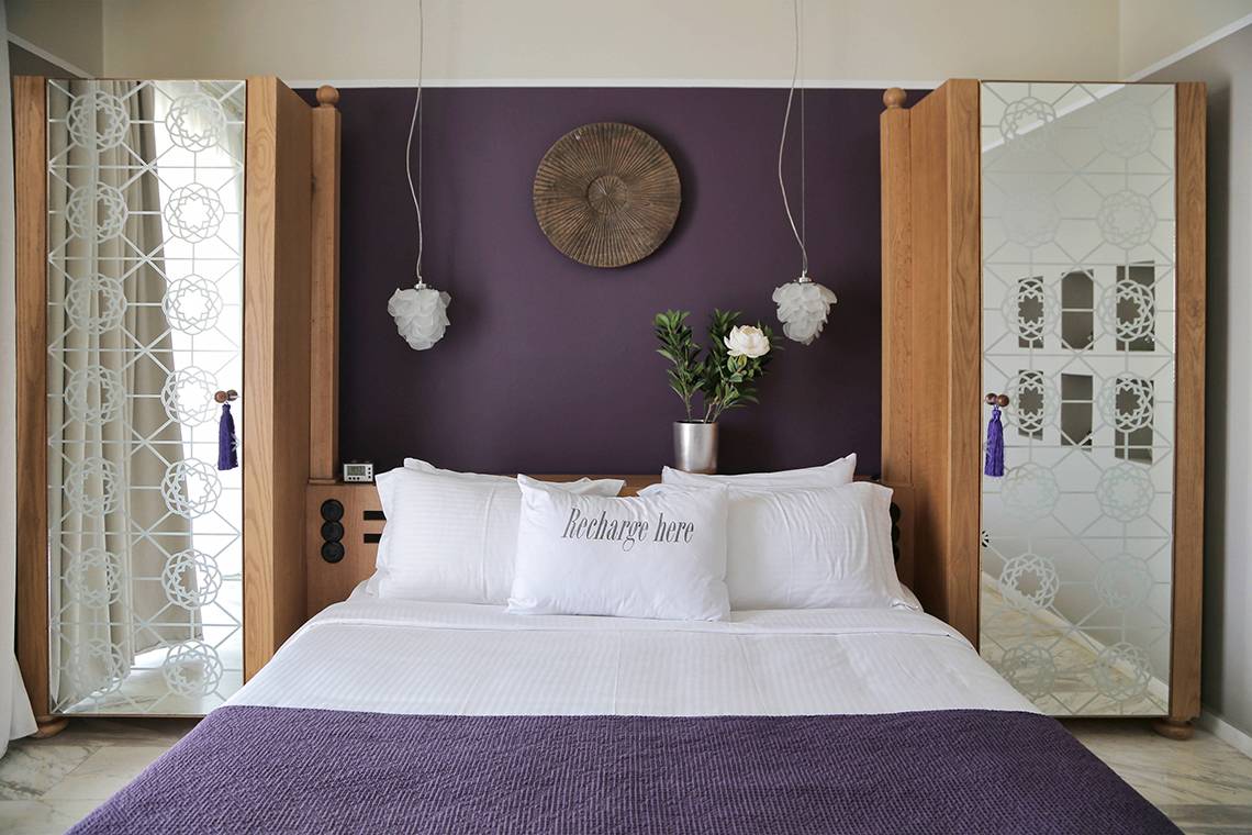 Schlafzimmer im Domes of Elounda, Autograph Collection mit lila Wand, weißen Kissen und Deko